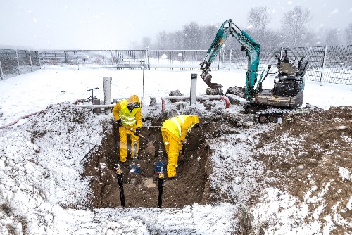 Construction works dig at a site for a home addition in winter. 